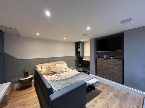 Schlafzimmer mit einem Bett, einem Schreibtisch und einem TV in der Unterkunft VOS Lodge Leeds UK in Hunslet