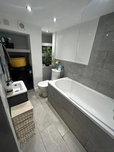 a bathroom with a tub and a toilet and a sink at VOS Lodge Leeds UK in Hunslet