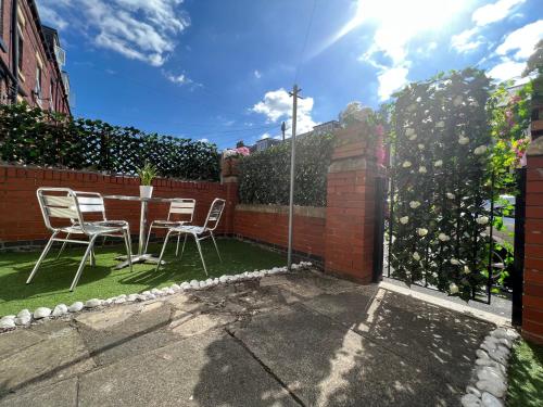eine Terrasse mit einem Tisch, Stühlen und einem Zaun in der Unterkunft VOS Lodge Leeds UK in Hunslet