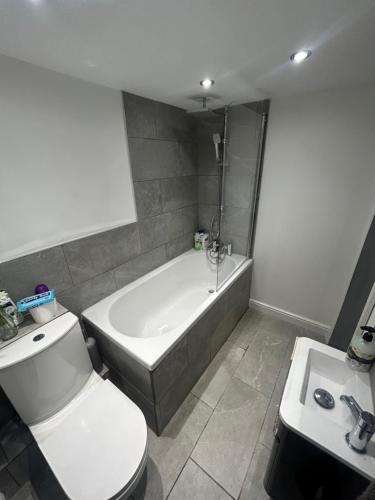 ein Badezimmer mit einer Badewanne, einem WC und einem Waschbecken in der Unterkunft VOS Lodge Leeds UK in Hunslet