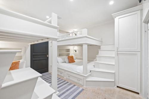a white bedroom with a bunk bed and stairs at Serenity Now - Private Pool,5 Bikes,Gulf Views, Steps to the Beach and Seaside! in Seagrove Beach