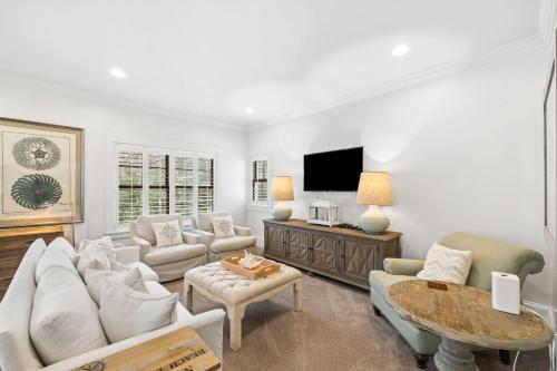 a living room with white furniture and a flat screen tv at Serenity Now - Private Pool,5 Bikes,Gulf Views, Steps to the Beach and Seaside! in Seagrove Beach