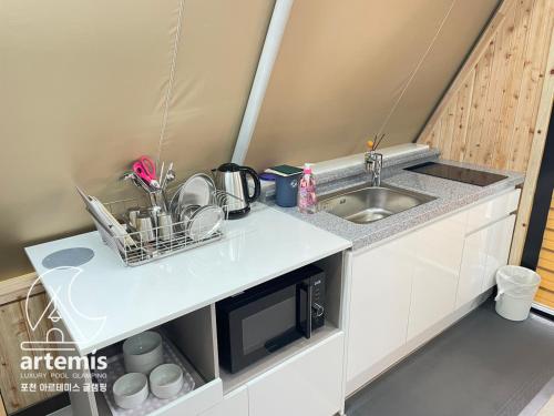 uma pequena cozinha com um lavatório e um micro-ondas em Pocheon Artemis Glamping em Pocheon