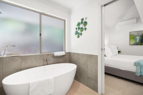 La salle de bains est pourvue d'une baignoire et d'un lit. dans l'établissement Something Wonderful 1 Bedroom By Belle Escapes, à Trinity Beach