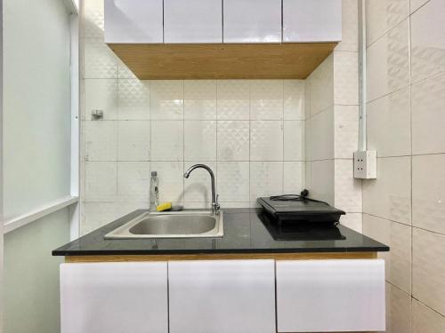 - une cuisine avec un évier et des placards blancs dans l'établissement Phuc Khang Apartment, à Hô-Chi-Minh-Ville