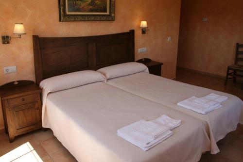 Un dormitorio con una cama con toallas blancas. en Casa Rural Las Canteras en Trujillo