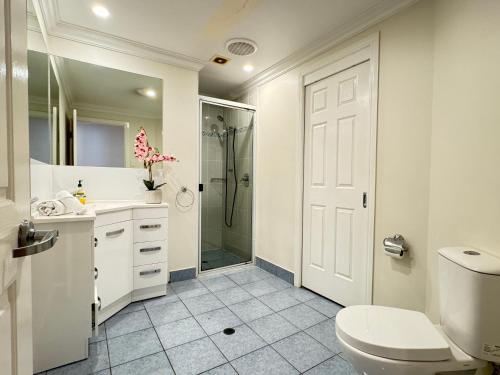 Un baño blanco con inodoro y ducha. en Townsville Apartments and Homes on The Strand, en Townsville