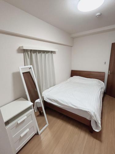 a small bedroom with a bed and a mirror at Jintai House in Hakata