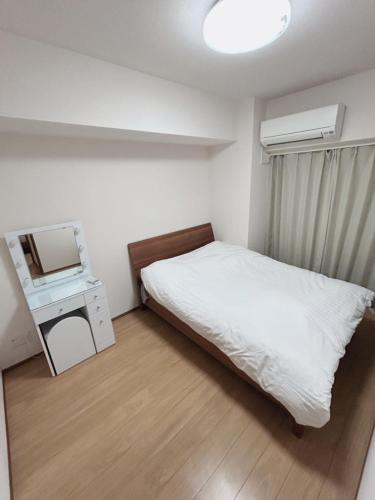 a bedroom with a bed and a desk with a television at Jintai House in Hakata