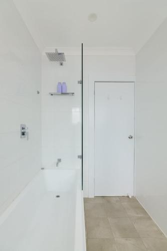 two white doors in a white room with a tile floor at Bondi Beachfront Bliss in Sydney