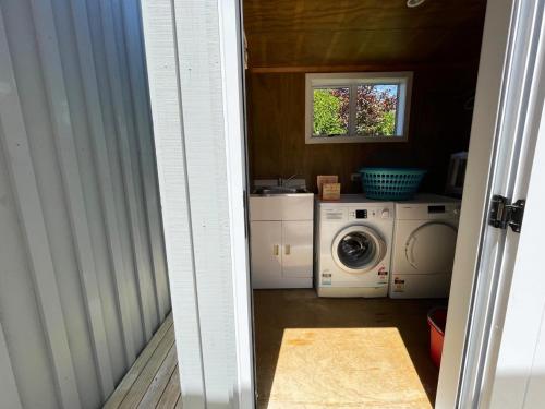 an open door to a laundry room with a washing machine at Oneroa Village Oasis - Stay Waiheke in Blackpool