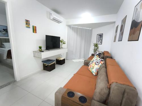a living room with a couch and a tv at The Place Beach Aparts: desperte os melhores sentidos a beira-mar e ao lado do centro de convenções. in Salvador