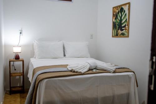 um quarto com uma cama com lençóis brancos e almofadas em Pousada Mangai em João Pessoa