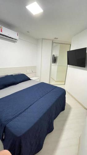um quarto com uma cama azul e um espelho em Apartamento Maceió- Jatiúca em Maceió