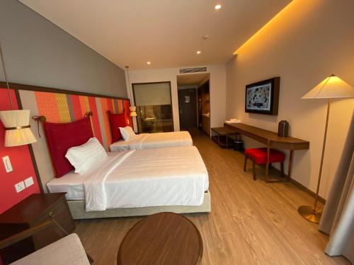 a hotel room with two beds and a desk at Apec Mandala Chambay Mũi Né in Phan Thiet
