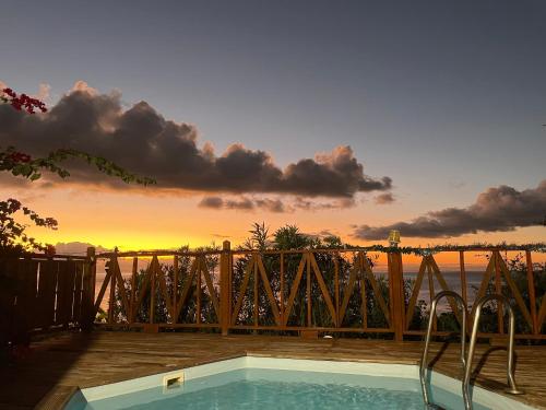 Una piscina con una puesta de sol al fondo en Bungalows Mathilde-non fumeur, en Bouillante