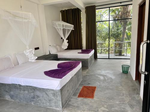 a bedroom with two beds and a large window at Blue Mountains View in Dambulla