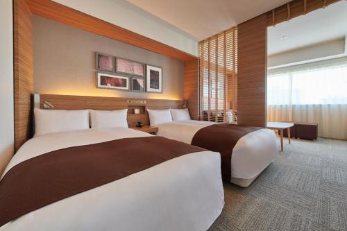a hotel room with two beds and a window at Cross Hotel Sapporo in Sapporo