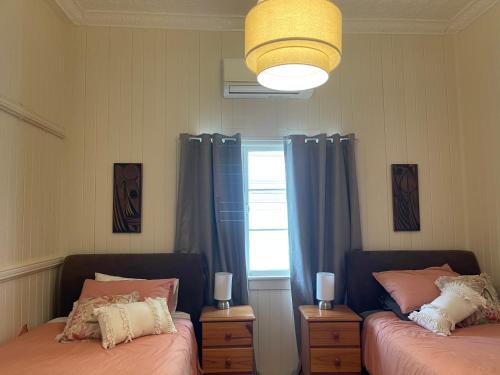 a bedroom with two beds and a window with blue curtains at VG’s BnB in Longreach