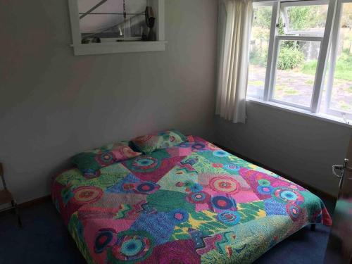a bed with a colorful comforter in a bedroom at Ako Retreat 
