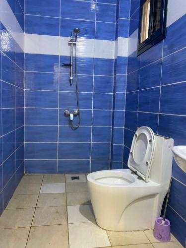 a blue tiled bathroom with a toilet and a sink at Résidence El Hadji Annexe in Dakar