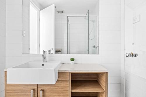 a white bathroom with a sink and a mirror at 2BR Apt in Strathfield Sleeps 6 in Sydney