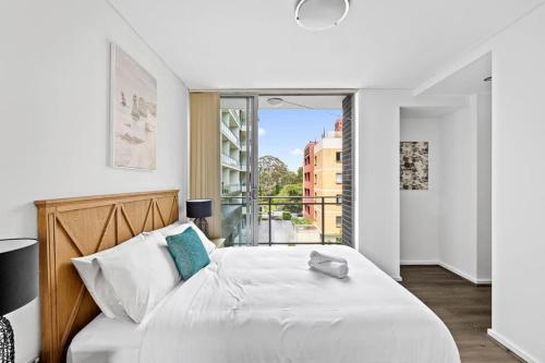 a bedroom with a large white bed and a balcony at 2BR Apt in Strathfield Sleeps 6 in Sydney