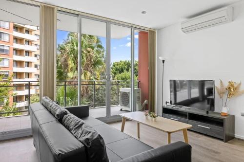 a living room with a couch and a large window at 2BR Apt in Strathfield Sleeps 6 in Sydney