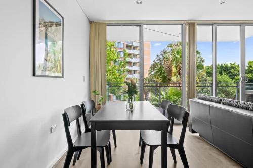 a dining room with a table and chairs and a large window at 2BR Apt in Strathfield Sleeps 6 in Sydney