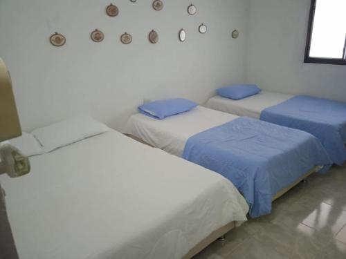 um quarto com três camas com lençóis azuis em Villa Concha em Pueblo Bello