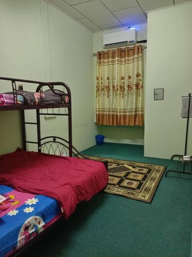 1 dormitorio con litera y alfombra en Nawlaa Homestay en Melaka