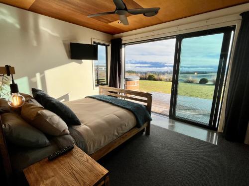 a bedroom with a bed and a large sliding glass door at Fiordland Eco-Retreat -- Panoramic Views -- Hot Tub in Te Anau