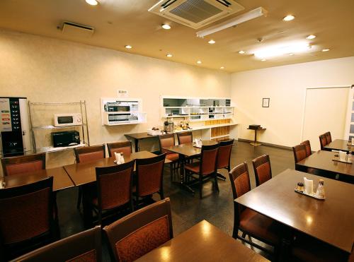 a restaurant with tables and chairs and a kitchen at Hotel LC Gifu Hashima in Hashima