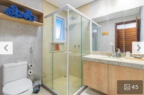 bagno con doccia in vetro e servizi igienici di Condomínio meridional a Tamandaré