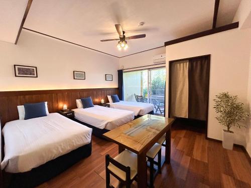 um quarto com duas camas e uma mesa e uma janela em Pension Sunset Beach em Nakijin
