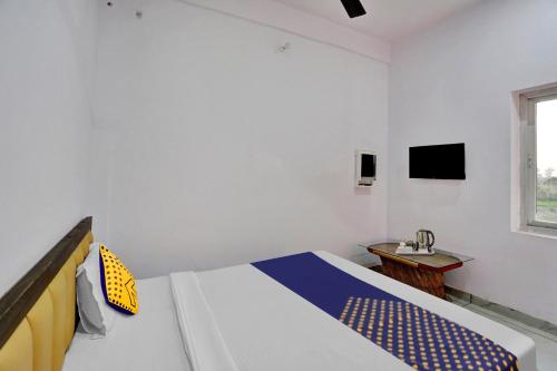 a bedroom with a bed and a desk and a television at OYO Flagship Sardarji Hotel And Restaurant in Bāzpur