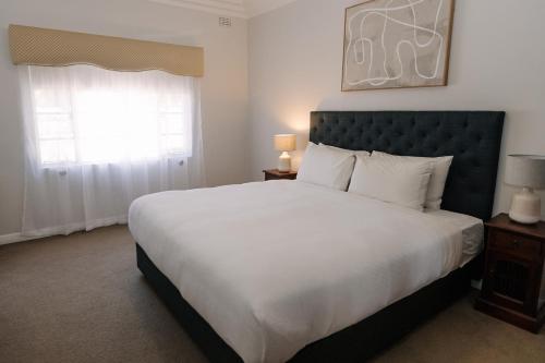 a bedroom with a large white bed and a window at Apartments on Morrow in Wagga Wagga