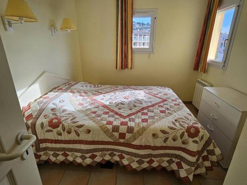 ein Schlafzimmer mit einem Bett mit einer Steppdecke darauf in der Unterkunft T2 avec Piscine, Vue Mer, Parking, à 200m de la Plage - FR-1-768-70 in La Garonnette-Plage