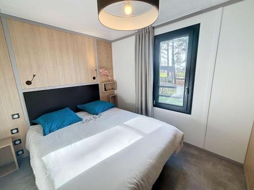 une chambre avec un grand lit blanc avec des oreillers bleus dans l'établissement Jullouville: Villa 4 pers, proche plage, piscine chauffée - FR-1-361-534, à Jullouville