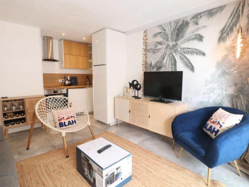 un salon avec une chaise bleue et une télévision dans l'établissement Studio cabine rénové avec clim et cuisine équipée à Sète - FR-1-472A-299, à Sète