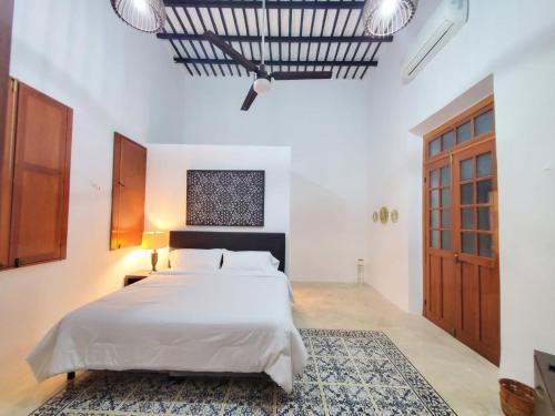 a bedroom with a large white bed and a wooden door at CASA XTABENTUN in Mérida