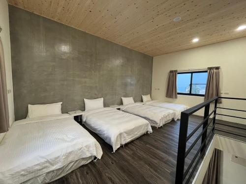 3 camas están alineadas en una habitación en Hey Castle B&B, en Xiaoliuqiu