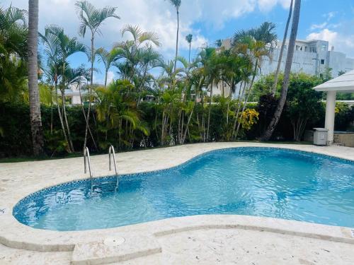 a swimming pool in a yard with palm trees at paradise close to the beach pool free parking,wifi- punta cana in Punta Cana