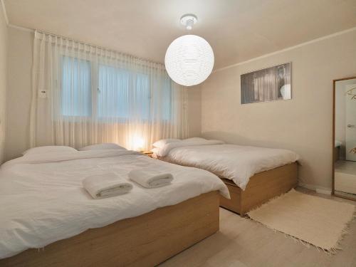 a bedroom with two beds and a large window at Hygge - Urban Hideout with four comfort beds in Seoul