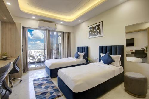 a hotel room with two beds and a balcony at FlxHo Quad - Luxury Studio Apart Hotel DLF Cyber City in Gurgaon