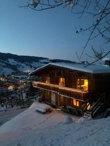 a house in the snow with lights on at SOMPTUEUX CHALET BARON MEGEVE VUE.Jaccuzi.4 mn a pied au centre in Megève