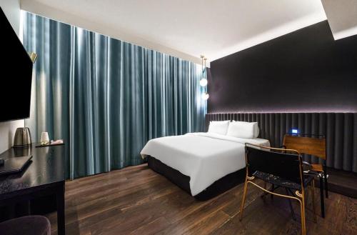 a bedroom with a bed and a desk and a chair at H Hotel Wangsimni in Seoul