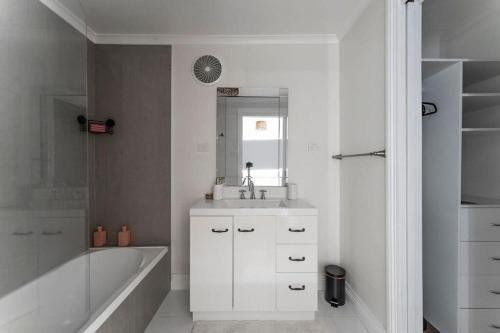 a white bathroom with a sink and a bath tub at View Point: Ocean Views & Near CBD in Burnie
