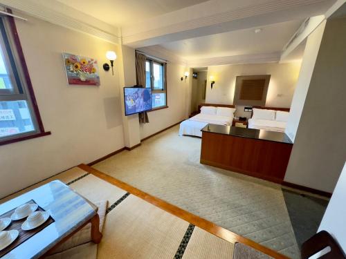 a hotel room with two beds and a flat screen tv at Tian Long Hotel in Jiaoxi