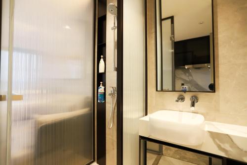 bagno con lavandino, specchio e doccia di 悦玺行政公寓-福田中洲湾店 a Shenzhen